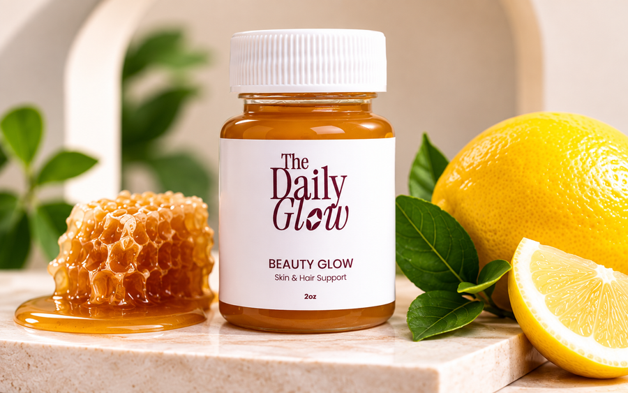 A jar of 'The Daily Glow' Beauty Glow skin and hair support supplement, styled with a honeycomb piece, honey, a whole lemon, and a lemon slice on a marble slab.